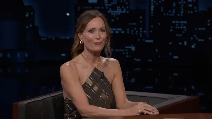 Leslie Mann sitting and smiling during an interview, sharing stories about celebrity encounters.