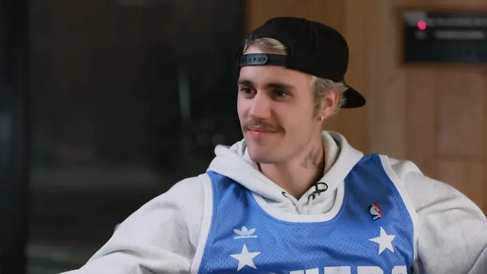 Justin Bieber wearing a backwards cap and jersey, discussing celebrity encounters