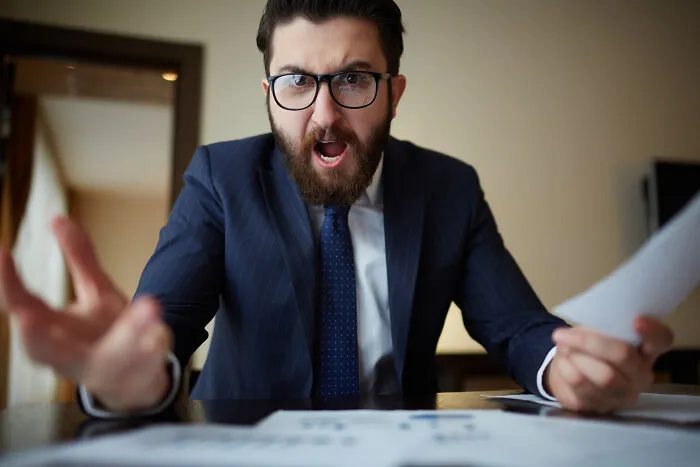 An angry boss shouting at work, showing signs that the economy is in trouble.