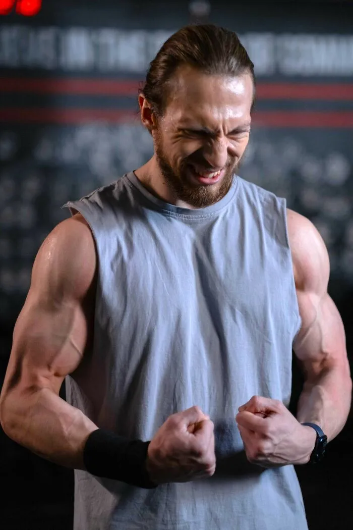 A man with intense expression flexing his biceps, showing the effort and glamour associated with Hollywood's image.