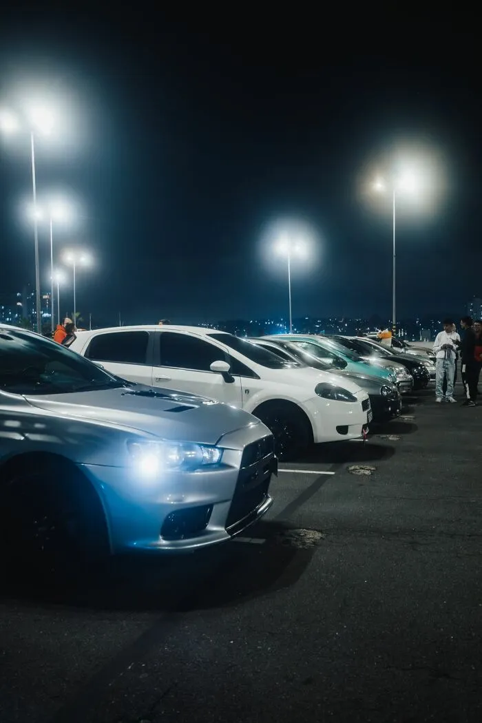 A row of cars parked at night under streetlights, symbolizing the fast-paced and luxurious side of Hollywood rumors.