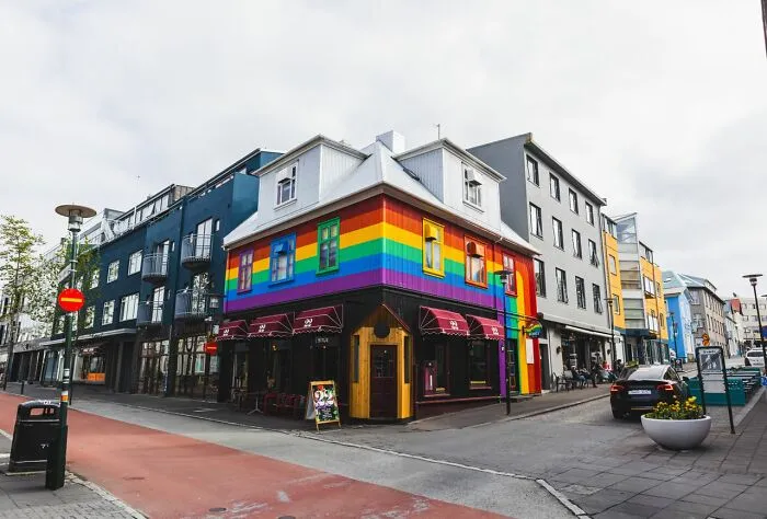 A brightly colored building painted with a rainbow, standing out in an urban setting, possibly linked to Hollywood glamor.