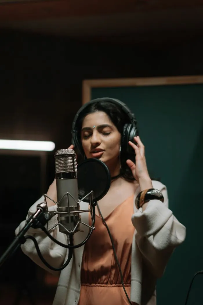 A female vocalist records in a studio, perhaps hinting at the glamorous image of Hollywood or its rumors.