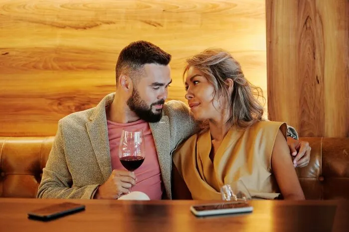 A couple enjoys a drink, potentially sharing Hollywood secrets or rumors in a candid moment.