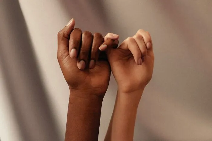 Two people of different races holding hands, showing empathy for strange patients in healthcare.