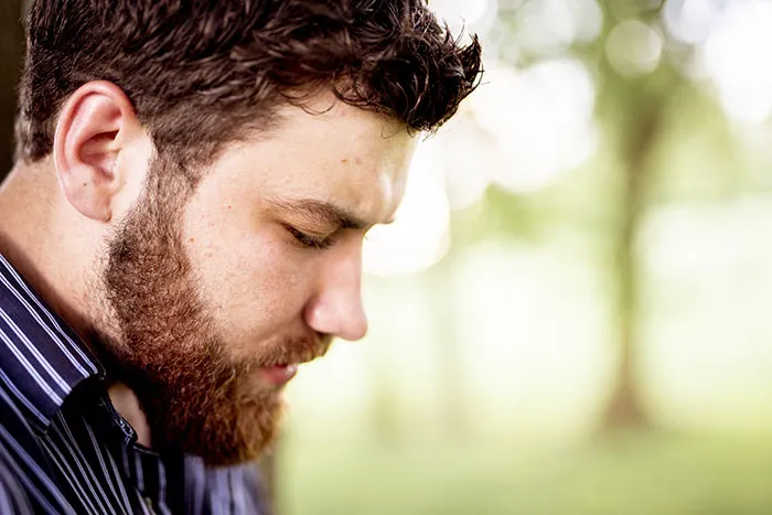A man looks down sadly, possibly after his marriage proposal was turned down.