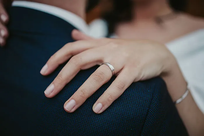 A woman's hand with a ring, resting on a man's shoulder after a marriage proposal.
