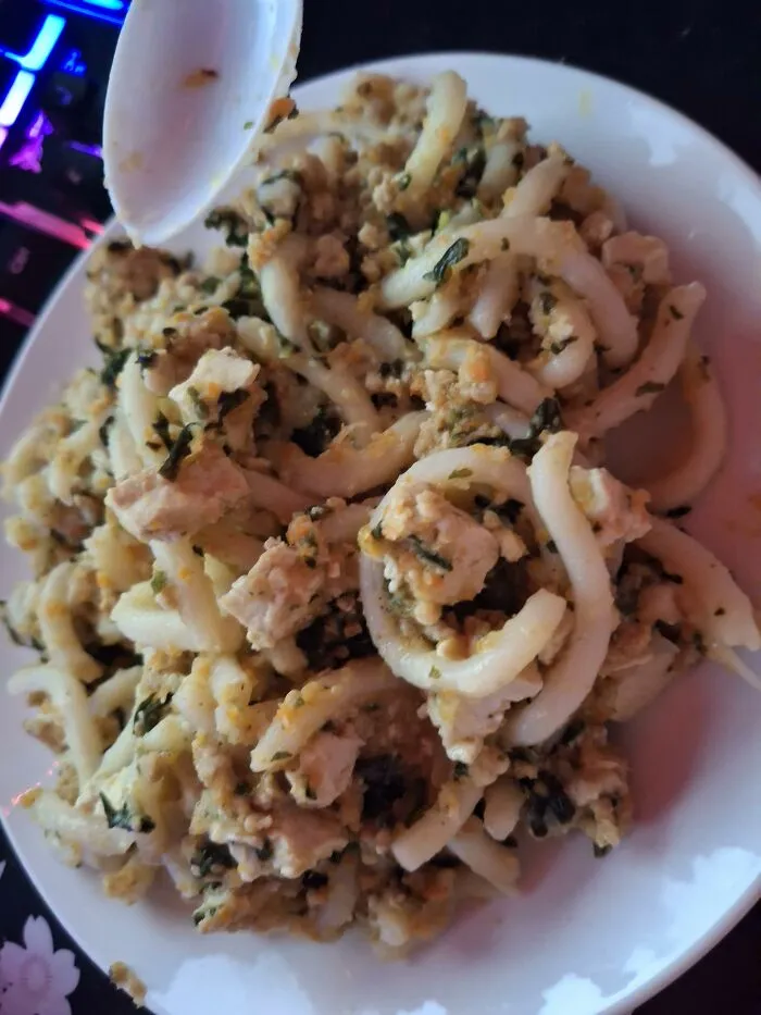 A plate of stir-fried noodles with crumbled tofu and greens, featuring unique food combinations