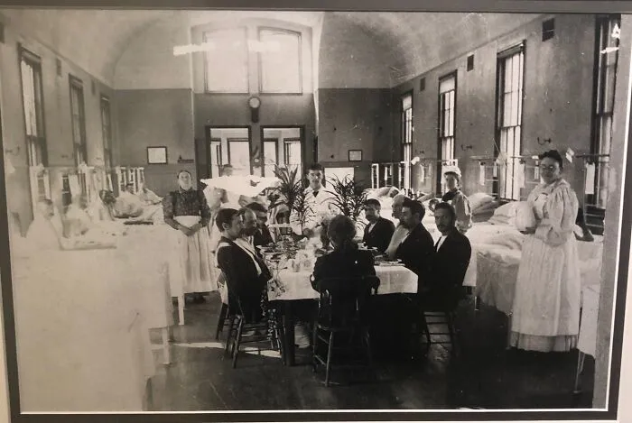 A black and white photo of doctors and nurses in a ward, showing medical history in action.
