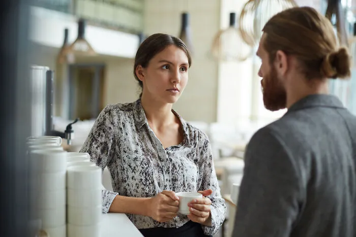 Woman holding cup listening during clever insult conversation