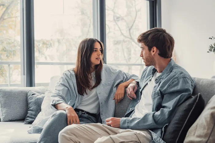A man and a woman talking on a couch, illustrating instances of subtle sexism.