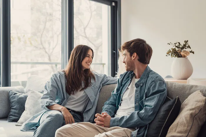 A happy young couple talking on a sofa, discussing the path to avoid marriage regrets.