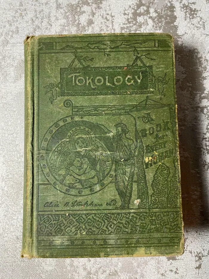 A worn green cover of Tokology, a book on maternity and health from medical history.