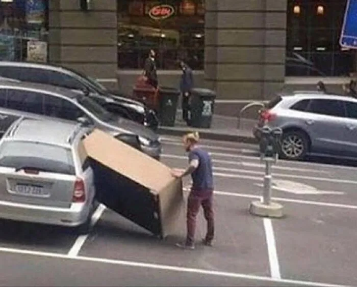 Person struggling with oversized box in parking lot moving fails