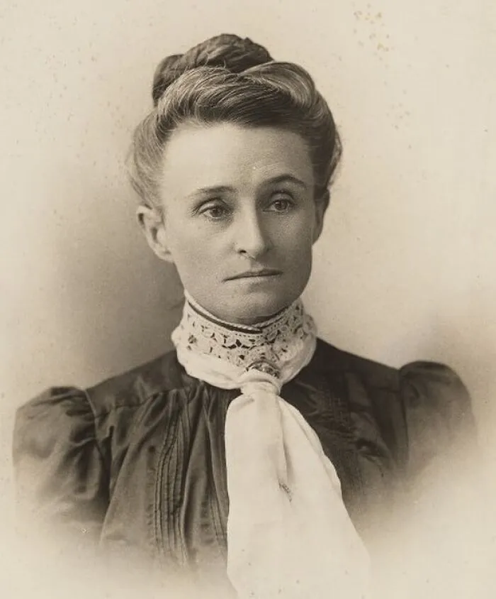 Sepia-toned portrait of a woman with an elegant updo and a lace cravat, highlighting women in history.