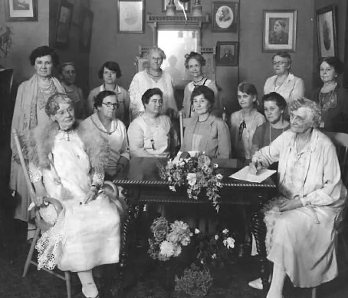 A group of Women-In-History signing documents at a table.