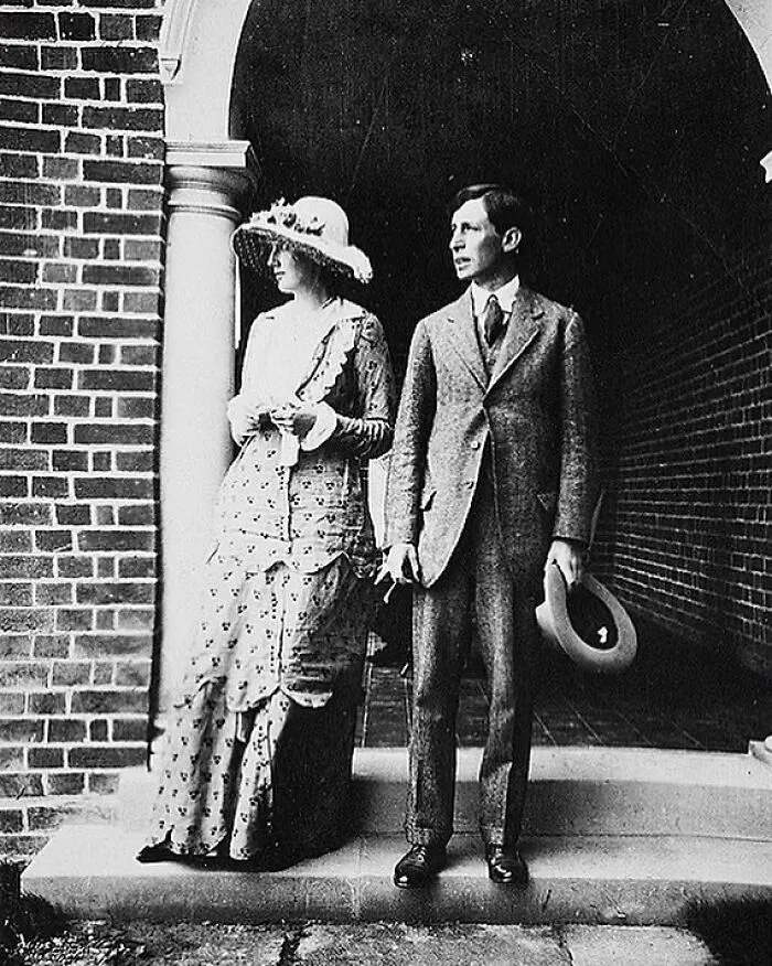 A black and white photo of Eleanor Roosevelt, a prominent figure among Women in History, standing beside her husband, Franklin D. Roosevelt, on a porch.