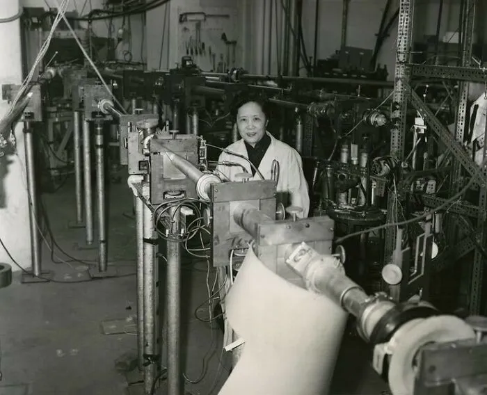 A black and white photo of Chien-Shiung Wu, a pioneering physicist, standing in a laboratory filled with scientific equipment, embodying Women in History.
