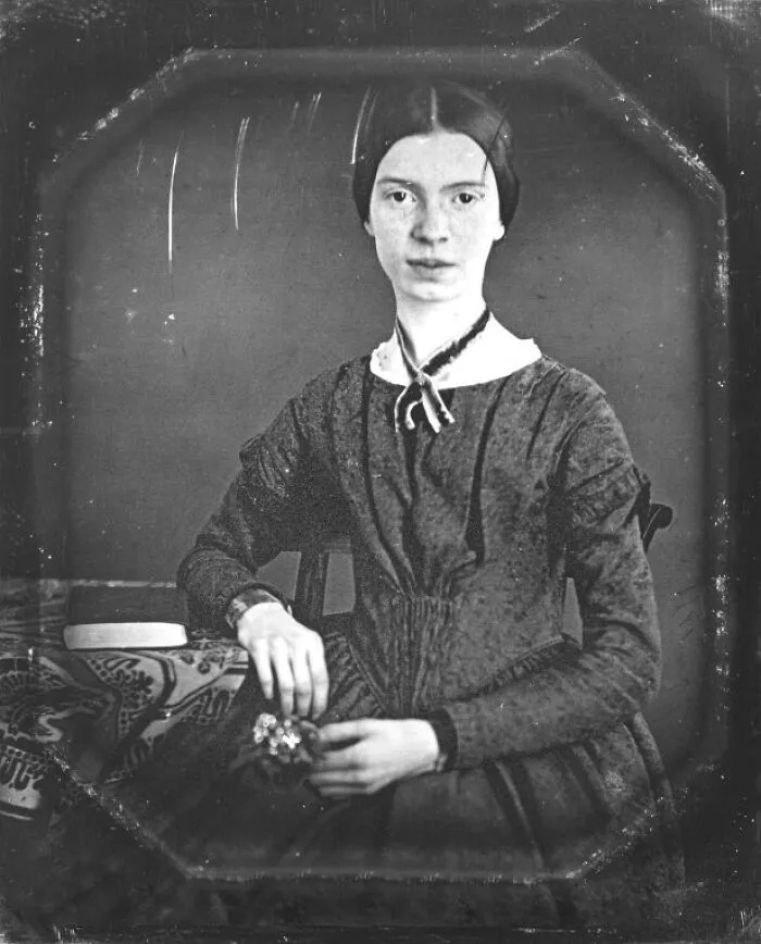 An old, black and white portrait of a young Emily Dickinson, a woman in history.