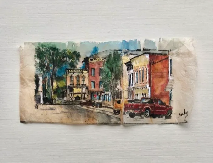 A detailed town street scene painted on used tea bags by artist Ruby Silvious