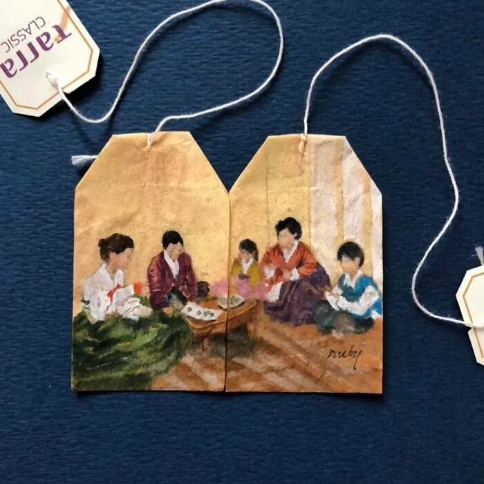 Delicate miniature paintings of a family gathering painted across two used tea bags.