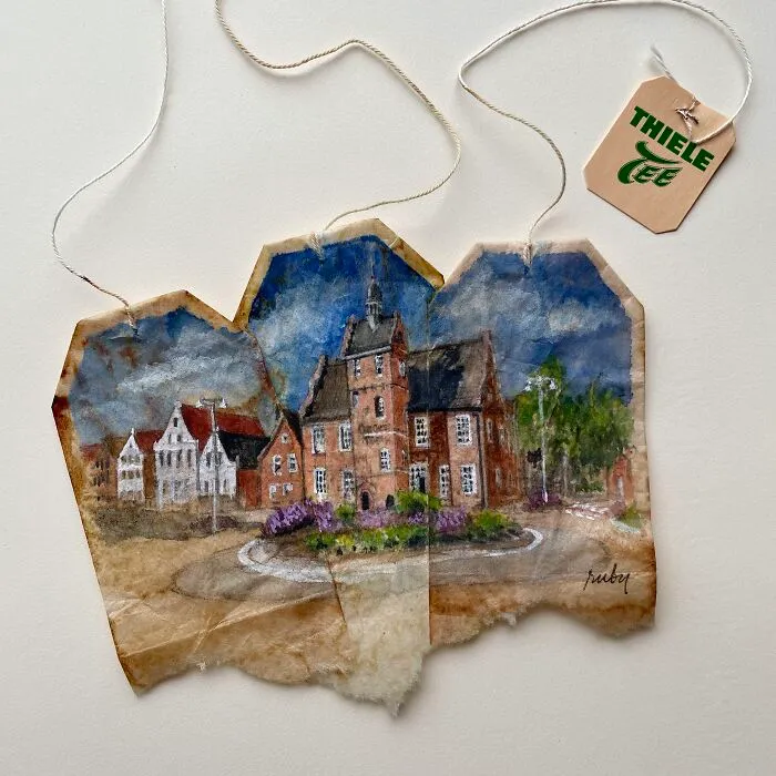 Delicate miniature paintings of historic brick buildings spanning across three used tea bags