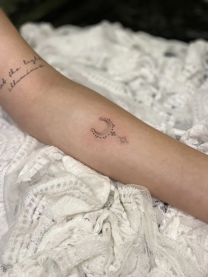 Minimalist crescent moon and star tattoo on forearm with dot work