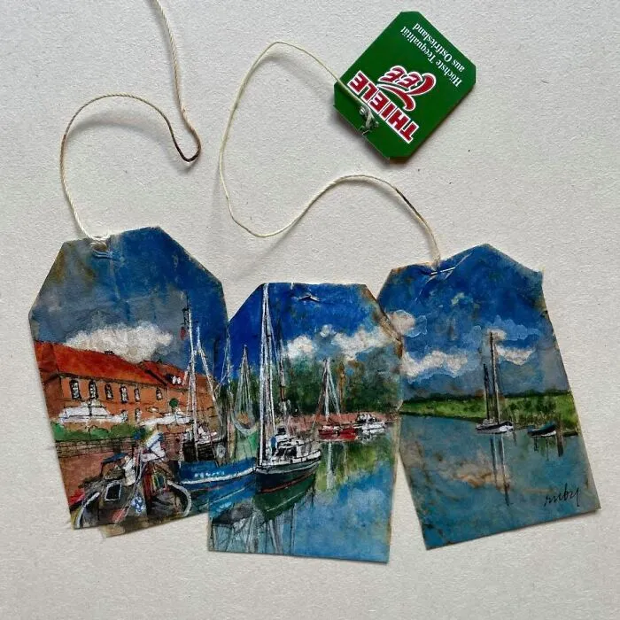 Miniature paintings on used tea bags depicting a harbor scene with sailboats by Ruby Silvious