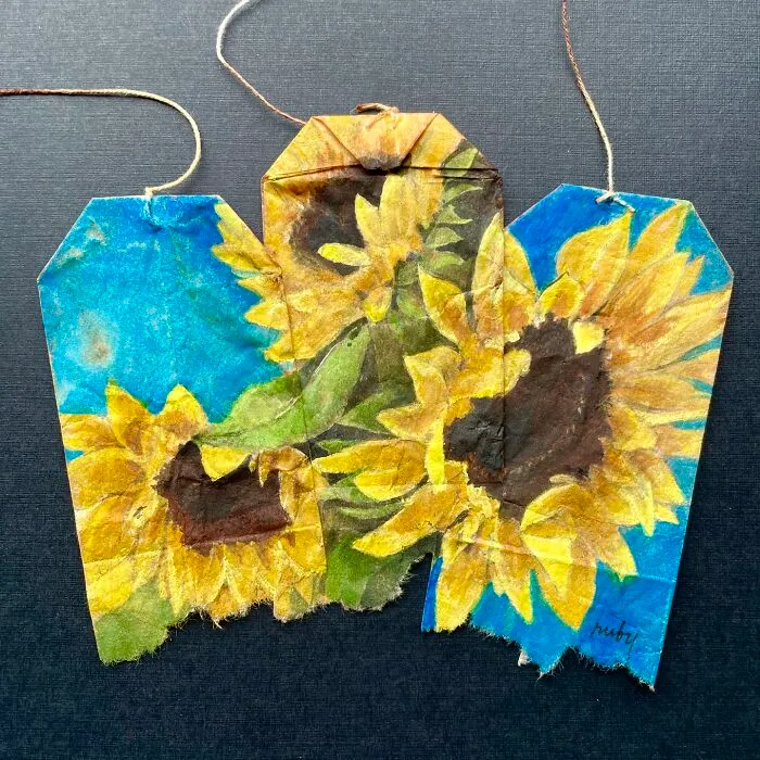 Bright yellow sunflowers featured in miniature paintings on used tea bags