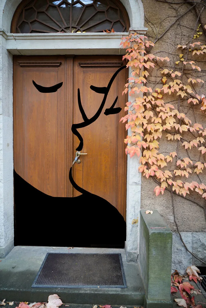 A pair of kissing faces painted in black on a wooden door, featuring elements of Abstract Sunday