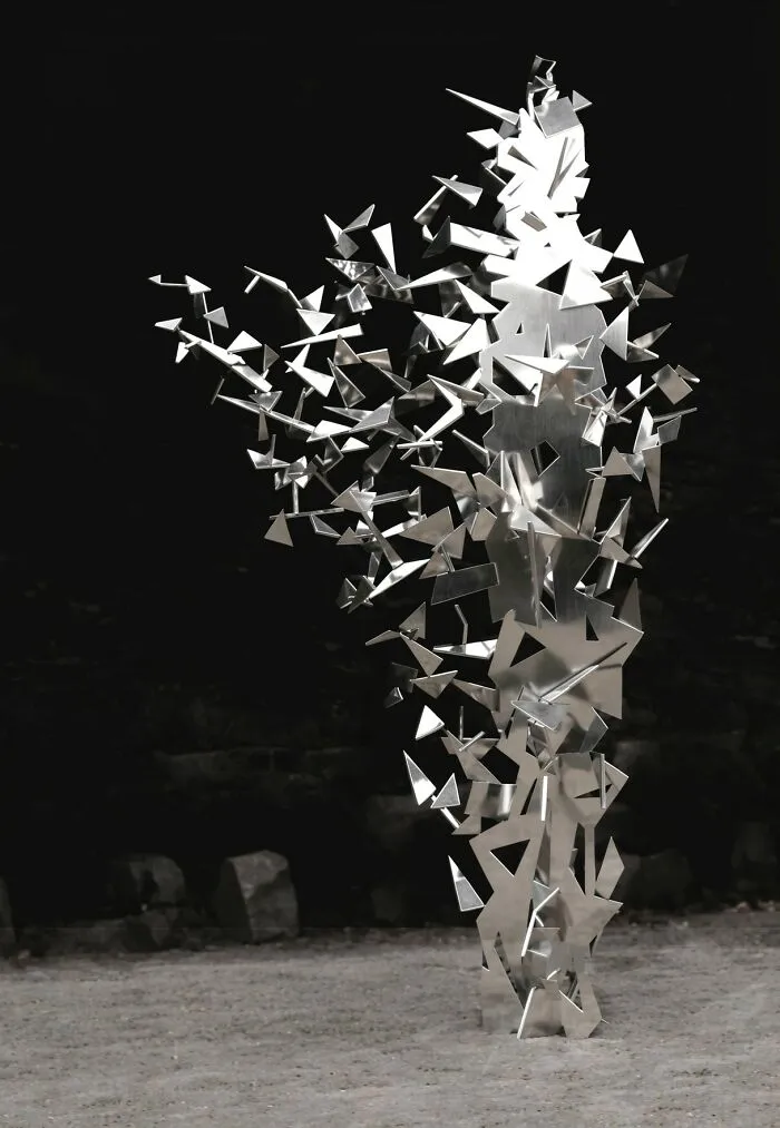 Close-up of reflective sculptures with scattered triangular pieces against a dark background
