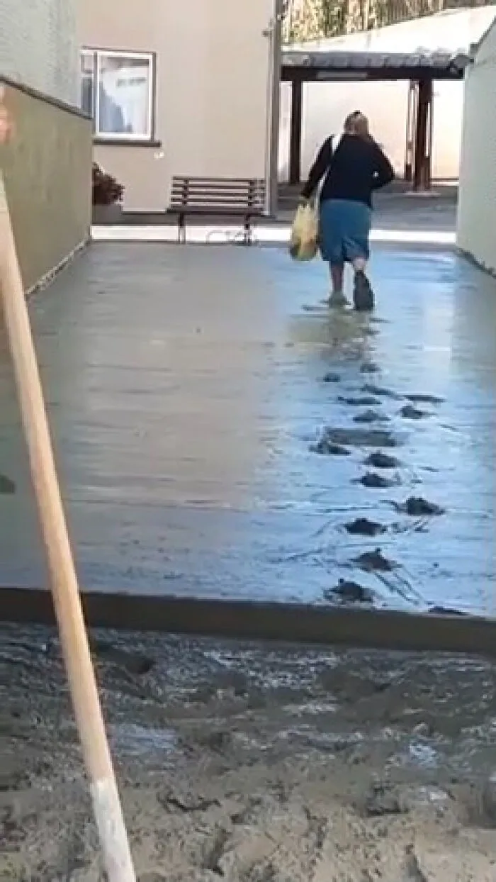 A woman walking on freshly poured concrete, demonstrating main character vibes as she leaves footprints behind.