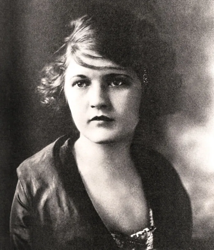 A black and white portrait of a young woman with short, wavy hair, looking forward, showcasing an influential woman in history.
