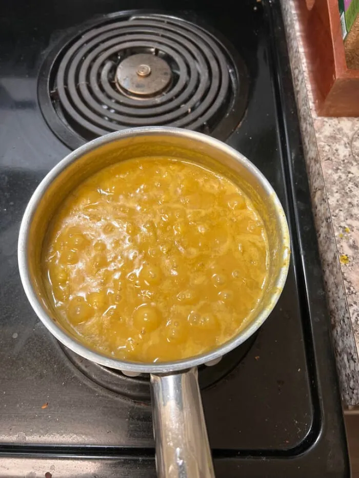 Orange soup bubbling in a pot on a stovetop, demonstrating unusual food combinations.