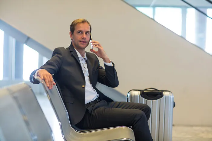 Businessman in suit sitting and talking on phone at airport
