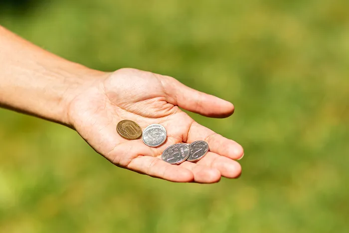 An open hand holds a few coins, illustrating a cheap budget and saving money.