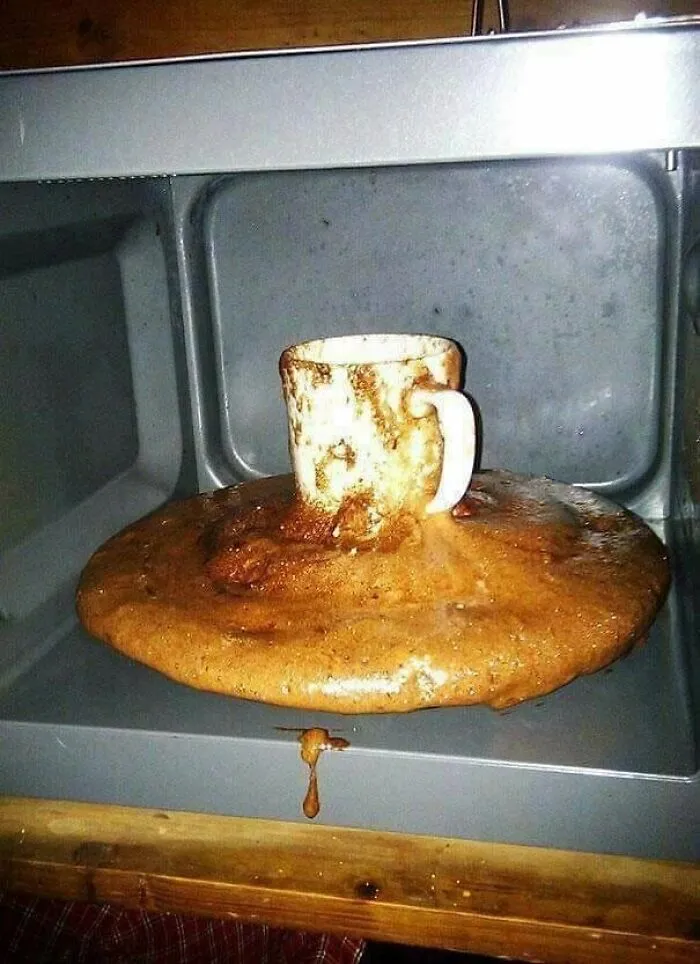 Microwave disaster with overflowing coffee cup and burnt food mess