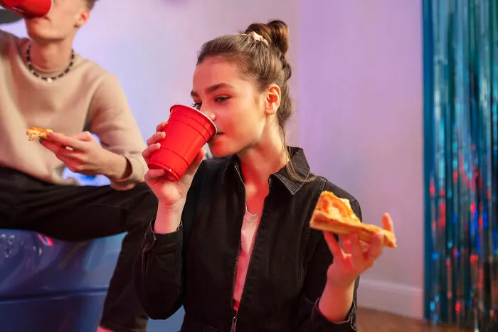 A young woman drinking from a red plastic cup, showcasing cheap ways to party with friends