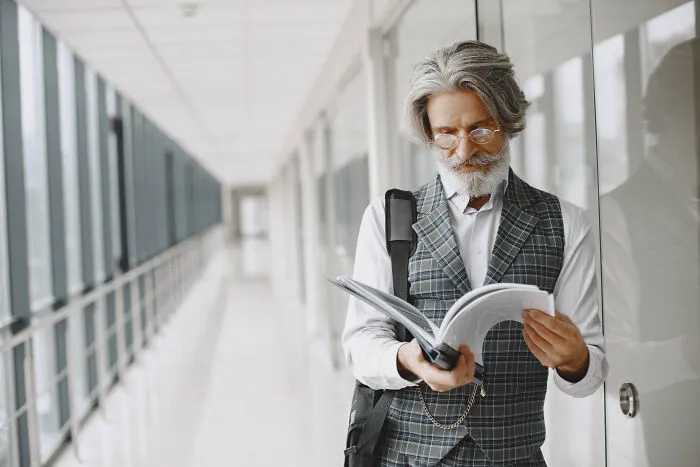 Distinguished gentleman reading a document in a hallway, symbolizing life paths of smart kids.