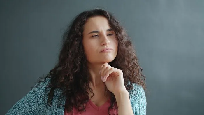A thoughtful woman with curly hair pondering micro-aggressions and their subtle impact.