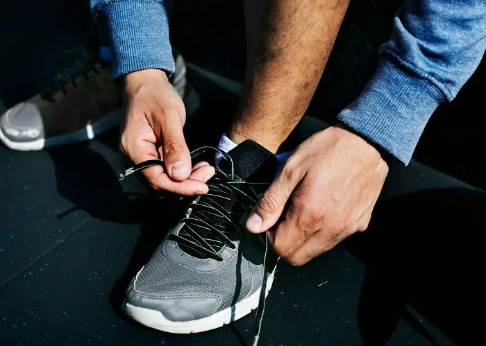 A man tying his running shoe, symbolizing readiness or escape from daily micro-aggressions.