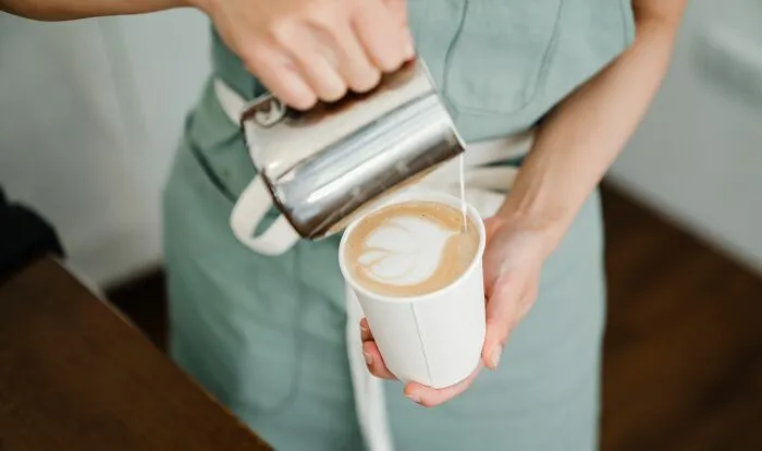 Barista pouring latte art into a coffee cup, subtly relating to micro-aggressions.