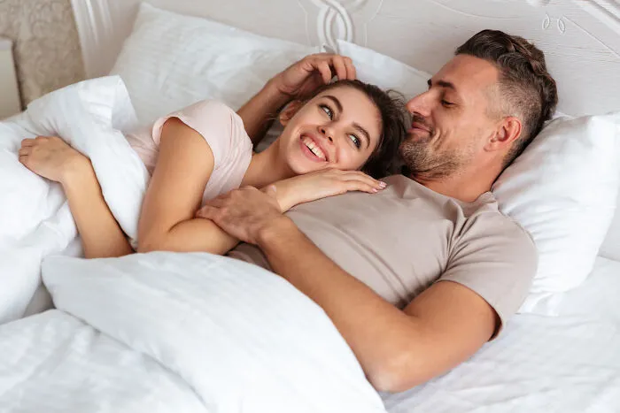 A happy couple smiling in bed, representing a close relationship with a partner.