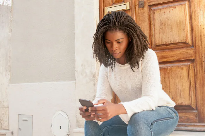 Concerned woman staring at her phone, discovering creepy things people did to a partner.