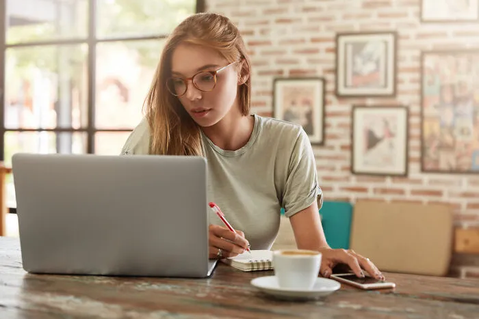 A focused woman working on a laptop, perhaps planning something secret for her partner.