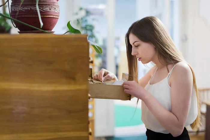 A woman searches through a wooden drawer, representing unsettling and creepy things someone might hide.
