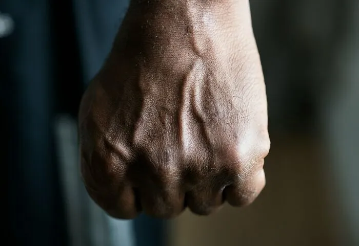 Close-up of a man's clenched fist, symbolizing the intense emotions lawyers may feel regarding their clients' decisions.