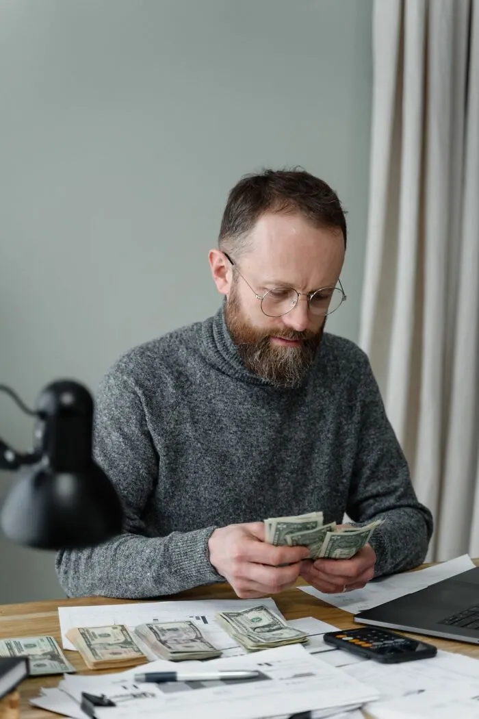 Man counting money at desk reflecting on family cut off financial issues