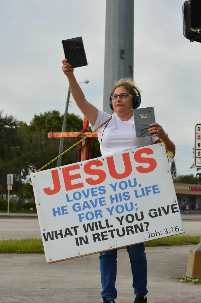 Protester holding Jesus sign and bibles advocating faith during family conflicts