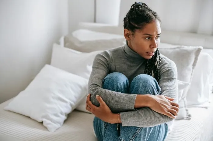 Woman sitting alone on bed looking sad family cut off reasons